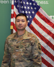 c/LTC Josue Reyes posing in front of green background and U.S. flag. 