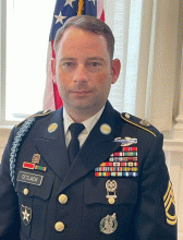 SFC Paul Tetlack posing in front of U.S. flag.